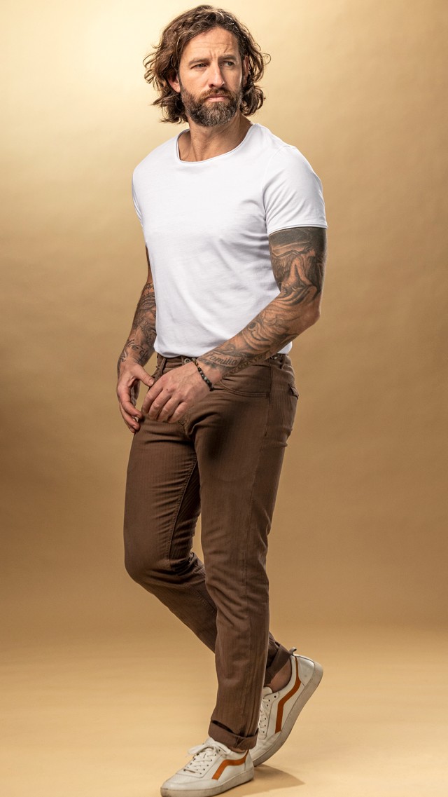 Mann bekleidet mit einem weißen Shirt und einer braunen Hose läuft durchs Bild