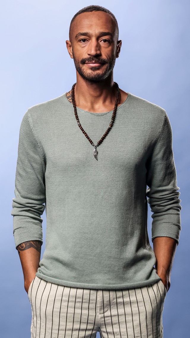 Ein Mann trägt einen hellblauen Strickpullover aus einem Baumwolle und Leinen Mix.