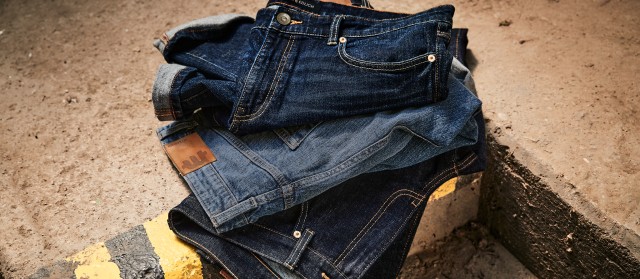 Drei übereinander gefaltete Jeans auf einem steinigen Untergrund.