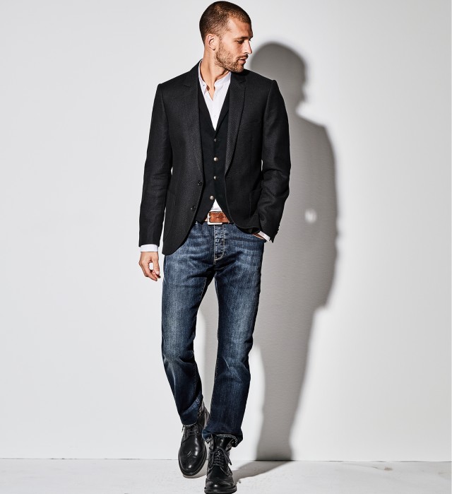 Mann in lässiger Pose der einen Sakko und Jeans trägt und zur rechten Seite schaut