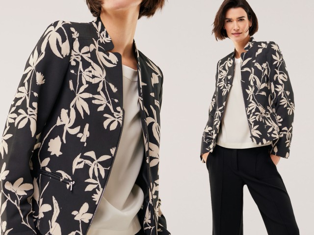 Frau trägt orangefarbenen Rollkragenpullover und blassrosa Blazer.