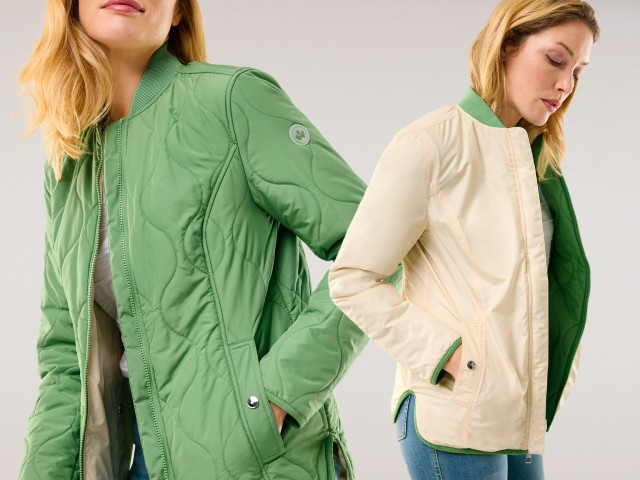 Frau mit blondem Haar im lila gestreiften Pullover und lila Steppjacke