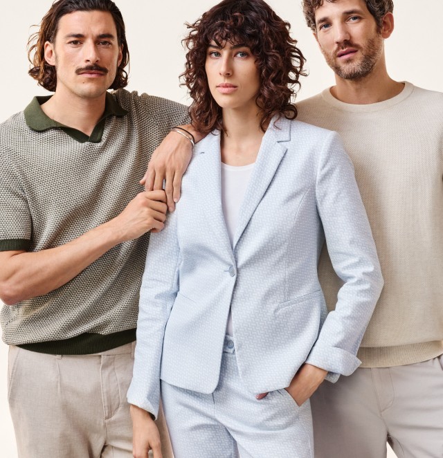 Zwei Männer und eine Frau in pastellfarbenen, eleganten bis lässigen Outfits.