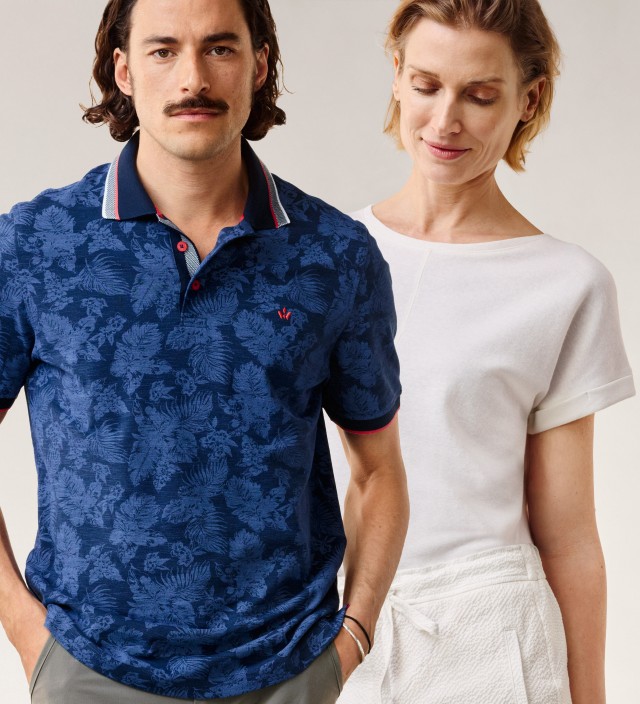 Mann in einem blau gemustertem Polo-Shirt und blonde Frau in weißem T-Shirt vor einem neutralen Hintergrund