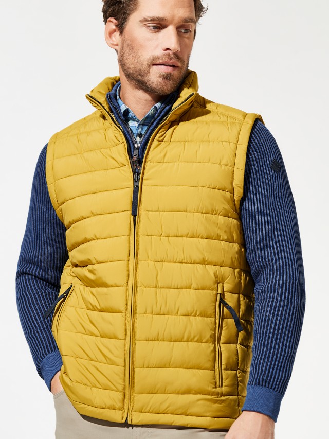 Mann trägt gelbe Weste über blauer Jacke