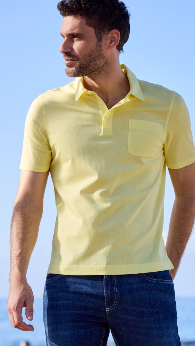 Dunkelhaariger Mann in Tausend-Poren-Polo in Citrus und blauer Ultraleicht-Jeans Klimakontrolle