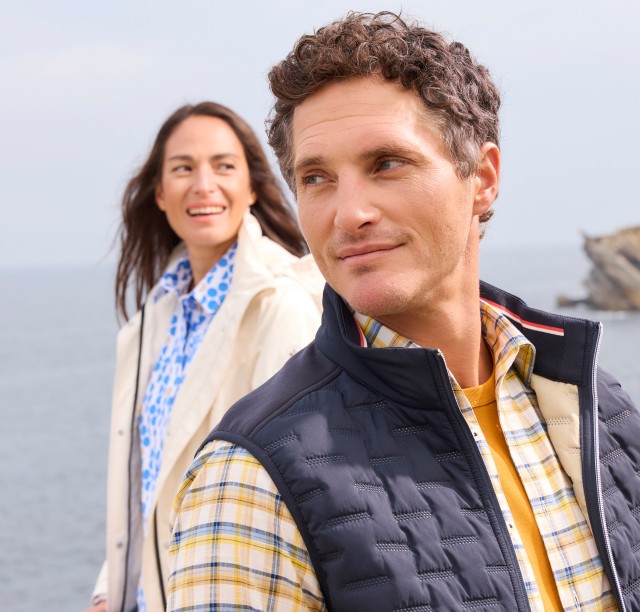 Mann im Vordergrund mit einer Frau hinter ihm am Meer.