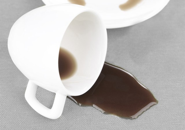 Umgekippte Kaffeetasse auf einer gepunkteten Tischdecke.