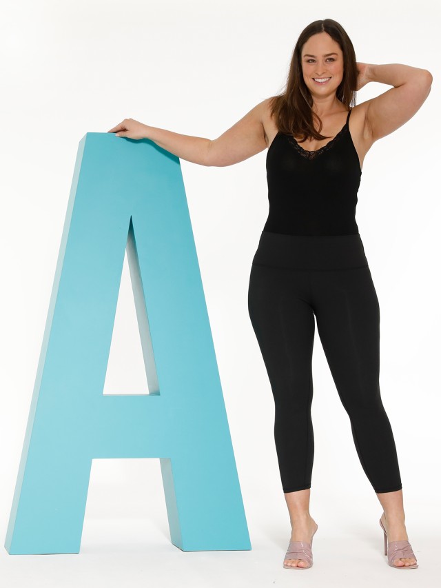 Frau steht neben einem großen blauen A-Buchstaben.