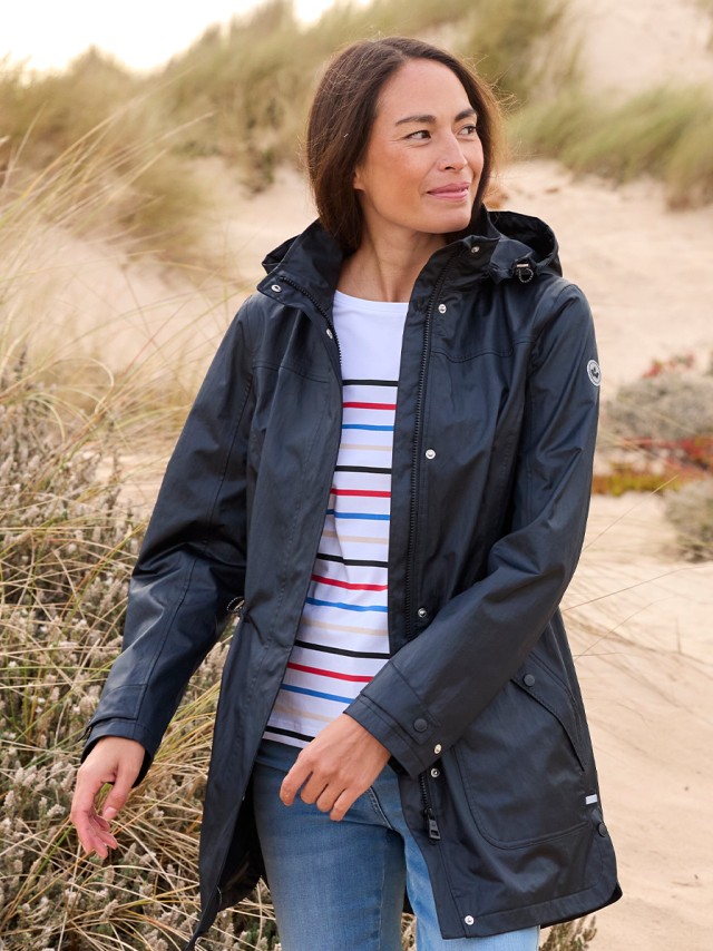Frau am Strand trägt einen Parka und eine Jeans