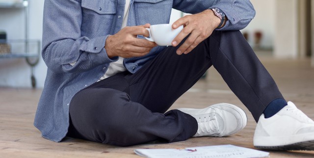 Mann sitzt im Schneidersitz auf dem Boden. Die Hose bleibt glatt.