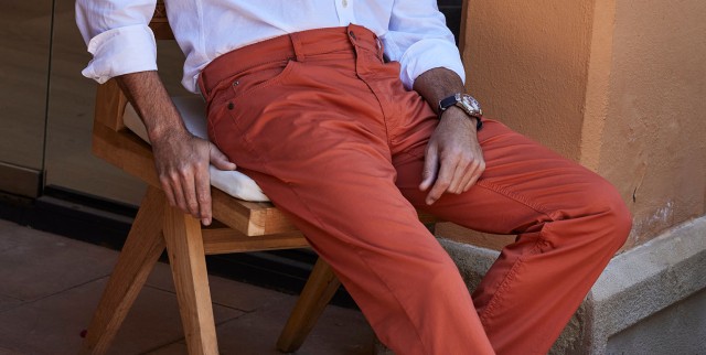 Mann sitzt mit einer ultraleicht Hose lässig auf einem Stuhl.