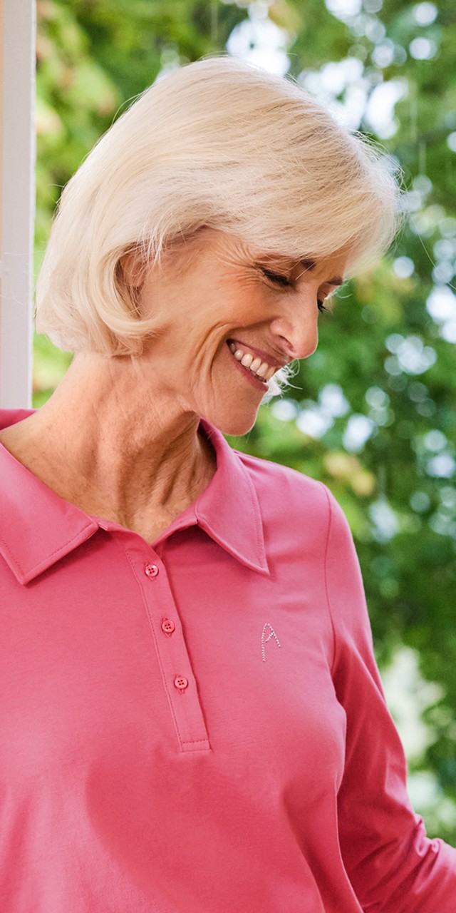Fröhliche Dame mit pinkfarbener Bluse genießt die frische Sommerluft.