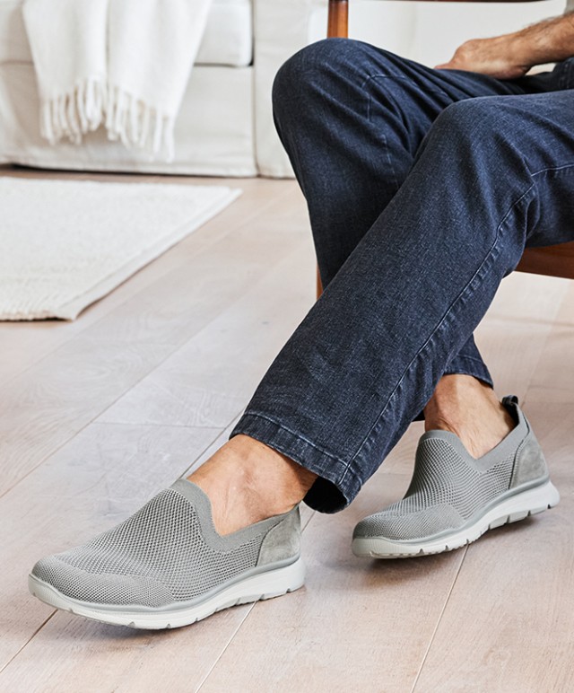 Helle Slipper werden von einem Herren getragen.