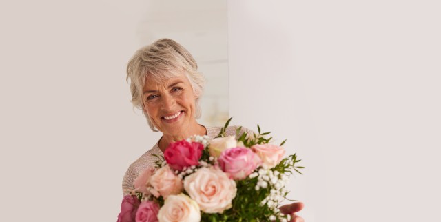 Fröhliche Mutter hat einen wunderschönen Blumenstrauß in der Hand.